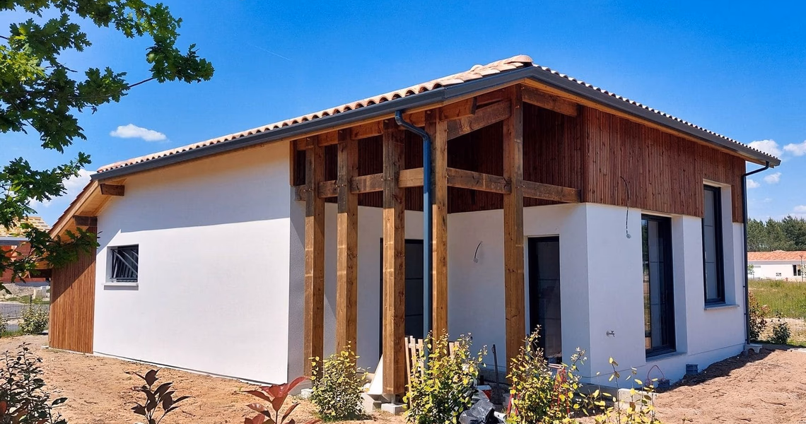 Façade de maison moderne aux murs blancs et bardage bois, dotée d'une structure de porche en poutres.