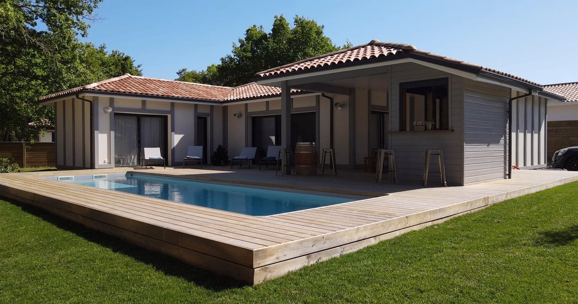 Maison moderne de plain-pied avec piscine creusée, grande terrasse en bois et bar extérieur.