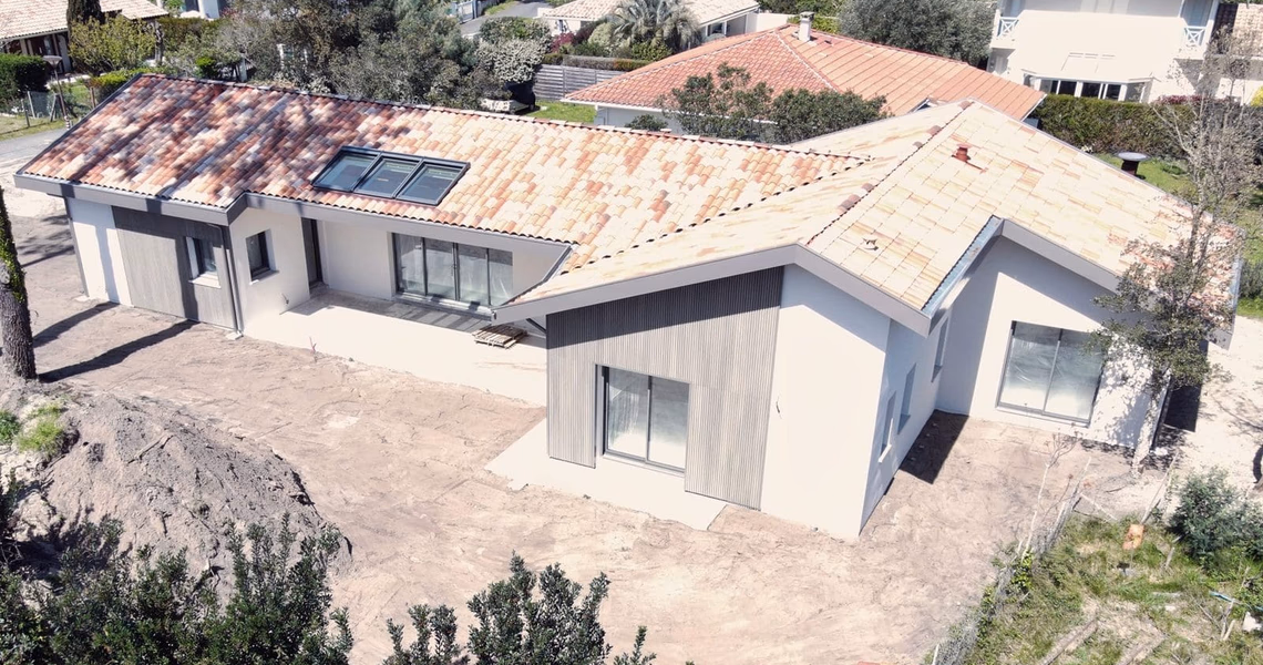 Vue aérienne de la villa en construction avec toiture en tuiles canal et bardage bois en façade.