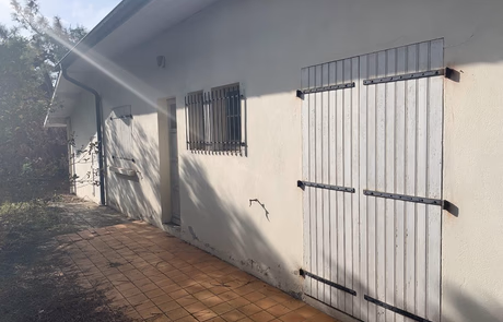 Façade d'une maison avec des volets en bois fermés et un mur blanc.