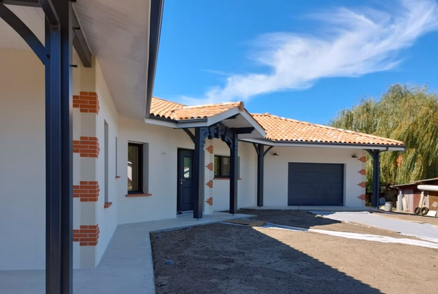 Façade de villa de plain-pied avec toiture en tuiles, porche à piliers sombres et garage fermé.
