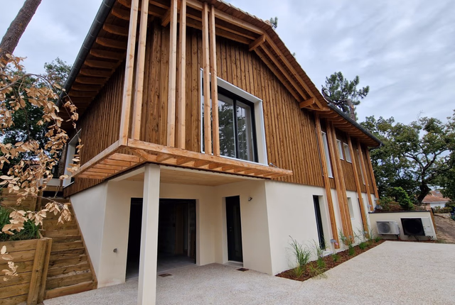 Façade d'une maison moderne à étage avec bardage en bois vertical et rez-de-chaussée blanc.