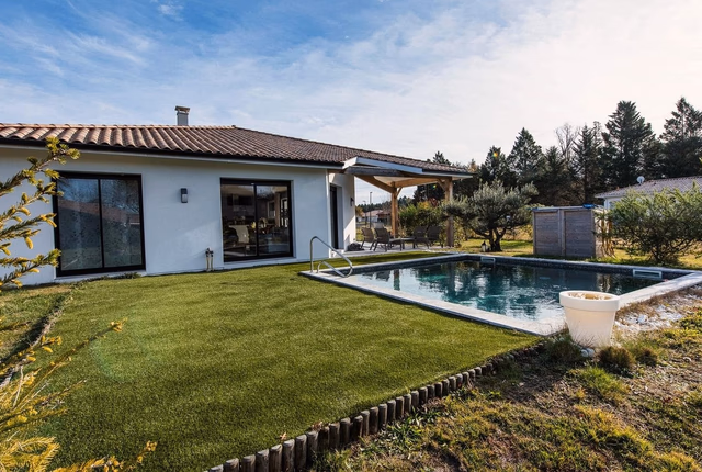 Maison de plain-pied blanche avec toiture en tuiles, grandes baies vitrées et piscine extérieure.