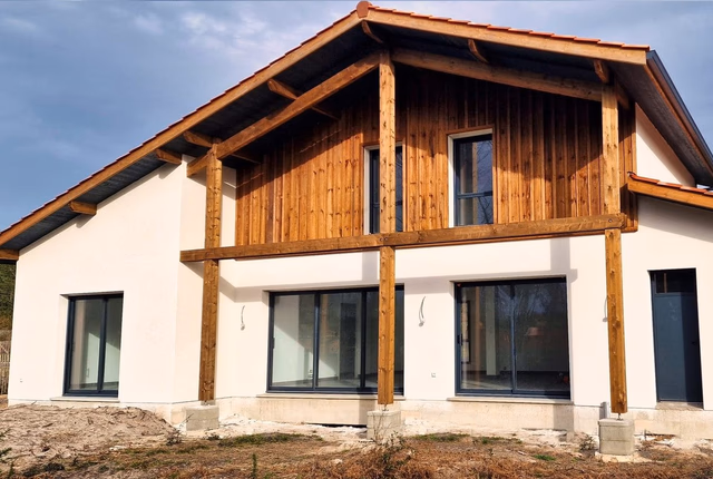 Villa contemporaine à étage en bois et enduit blanc avec larges baies vitrées et toiture en tuiles.