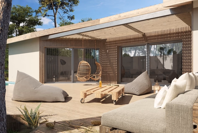 Grande terrasse en bois d'une maison avec pergola, canapé, poufs et larges baies vitrées.