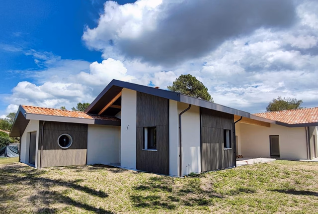 Façade contemporaine d'une villa de plain-pied avec parement bois, enduit clair et toiture en tuiles.