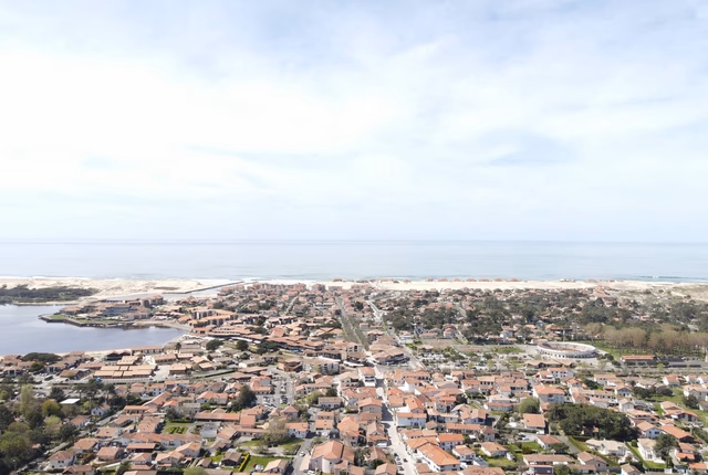 Vue aérienne panoramique de Vieux-Boucau-les-Bains montrant les toits de la ville et l'océan à l'horizon.