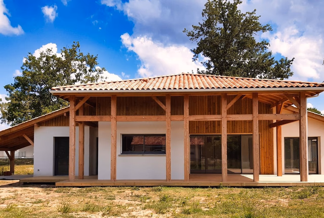 Façade de maison landaise contemporaine avec charpente en bois apparente et large terrasse couverte.
