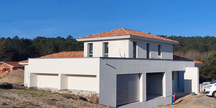 Vue d'une maison en construction Lit-et-Mixe avec enduit blanc et toiture mixte