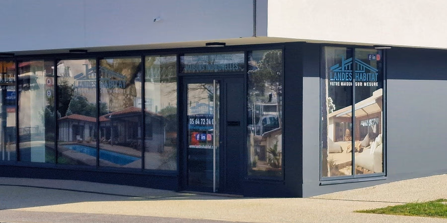 Vitrine de l'agence Landes Habitat avec des visuels de maisons et de piscines sur les vitres.