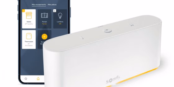 Un boîtier blanc Somfy et un smartphone affichant une application de contrôle domotique.