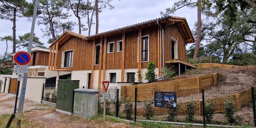 Vue de la façade avant d'une maison individuelle contemporaine avec bardage bois vertical, construite par Landes Habitat.