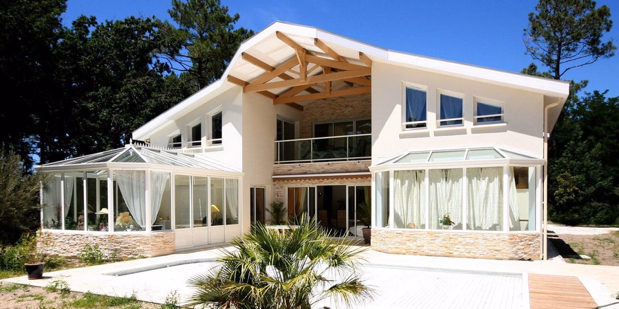 Maison R+1 contemporaine de 345 m² à Vieux-Boucau-les-Bains avec charpente apparente, double véranda et parement pierre - Construction Landes Habitat
