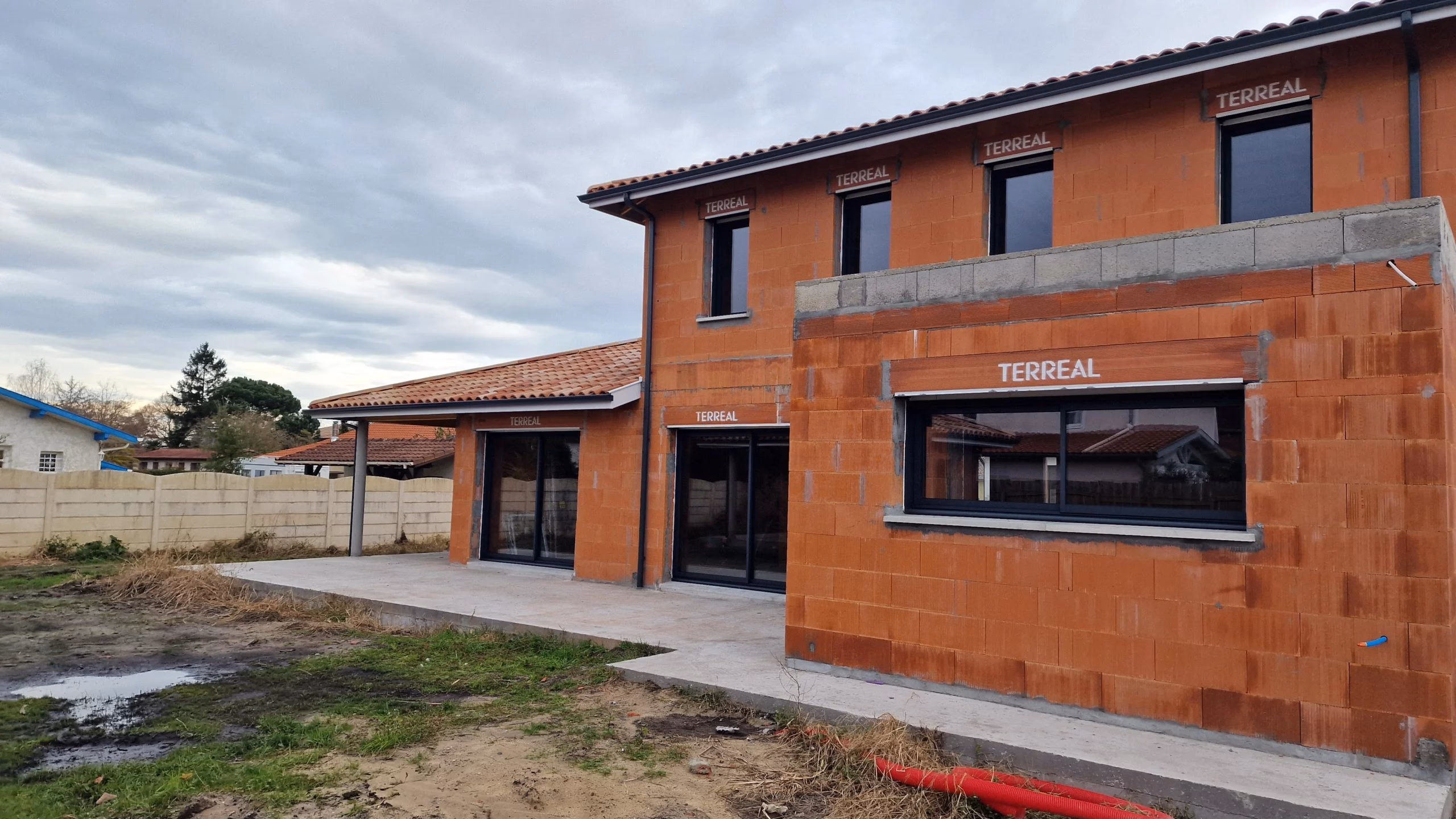 Chantier d'une grande maison individuelle avec terrasse couverte et toit en tuiles située à Tosse