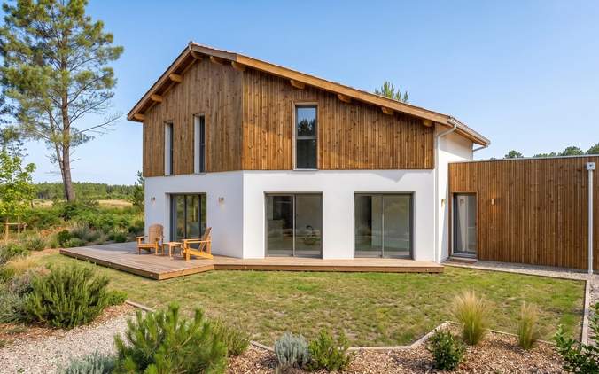 Maison moderne à deux étages avec crépi blanc, bardage bois vertical, grandes baies vitrées et terrasse en bois