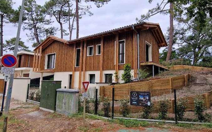 Vue de la façade avant d'une maison individuelle contemporaine avec bardage bois vertical, construite par Landes Habitat.