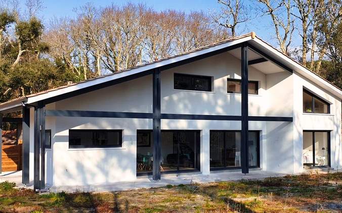 Façade moderne d'une maison familiale à Moliets avec bardage foncé et larges baies vitrées