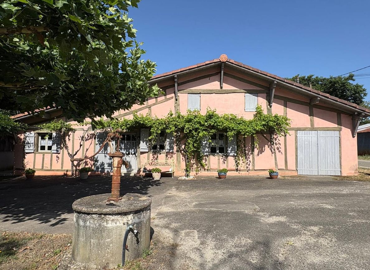 Maison landaise traditionnelle de plain-pied à colombages apparents et volets, avec treille de vigne et toiture à faible pente, dans les Landes (40)