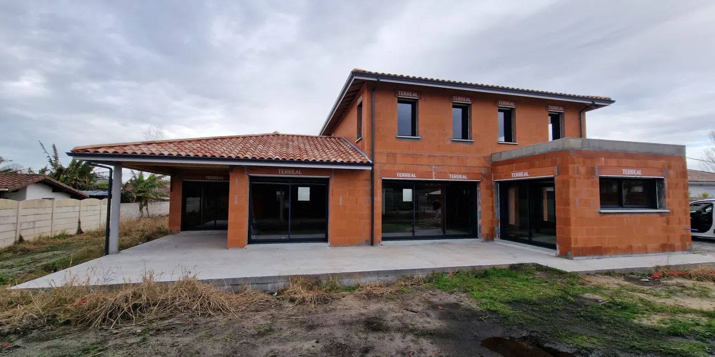 Vue arrière d'une maison contemporaine à étage avec extension toit plat en construction à Tosse par Landes Habitat.