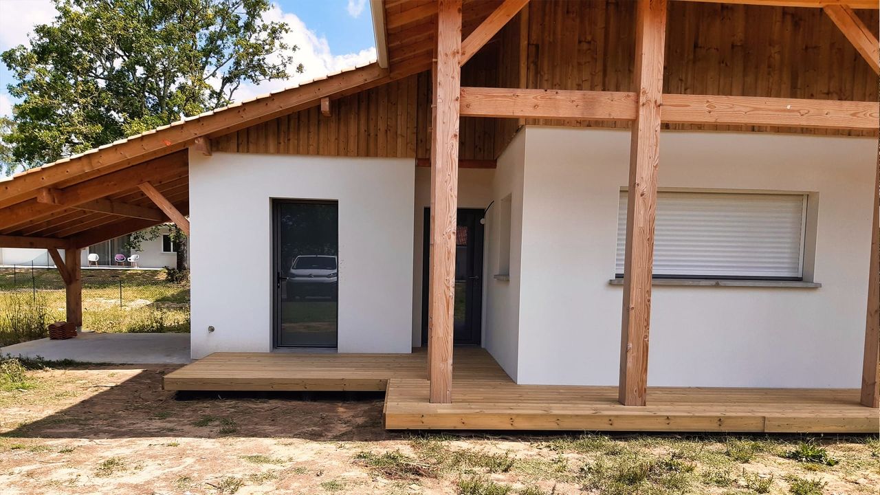 Façade d'une maison moderne avec une terrasse en bois et des colonnes en bois.