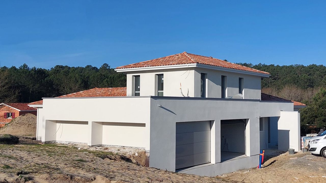 Vue d'une maison en construction Lit-et-Mixe avec enduit blanc et toiture mixte