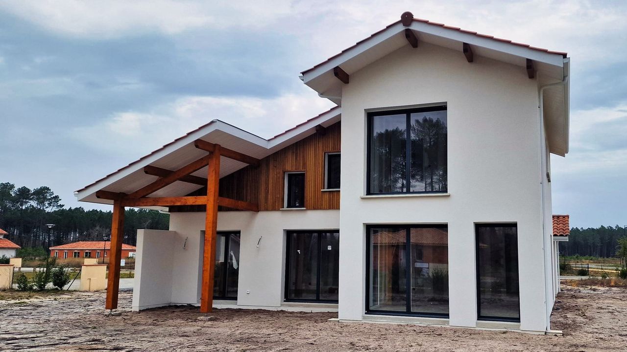 Maison moderne avec un toit en pente, des fenêtres en verre et des éléments en bois sur la façade.