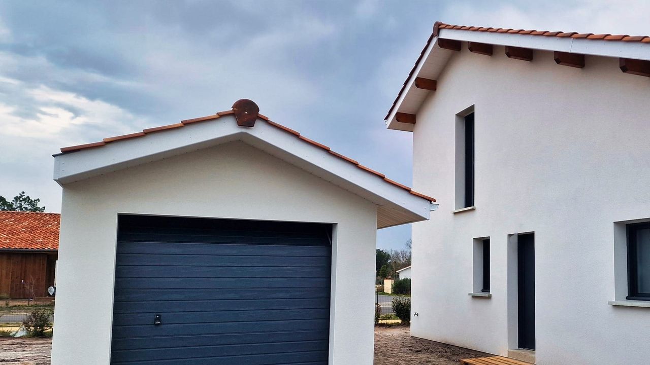 Maison moderne avec un garage attenant, présentant un toit en tuiles et des murs blancs.