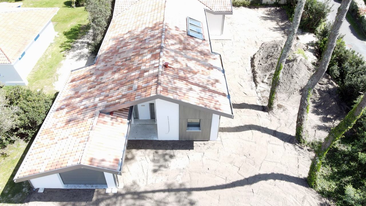 Vue aérienne d'une maison moderne avec un toit en tuiles et une allée en pierre.