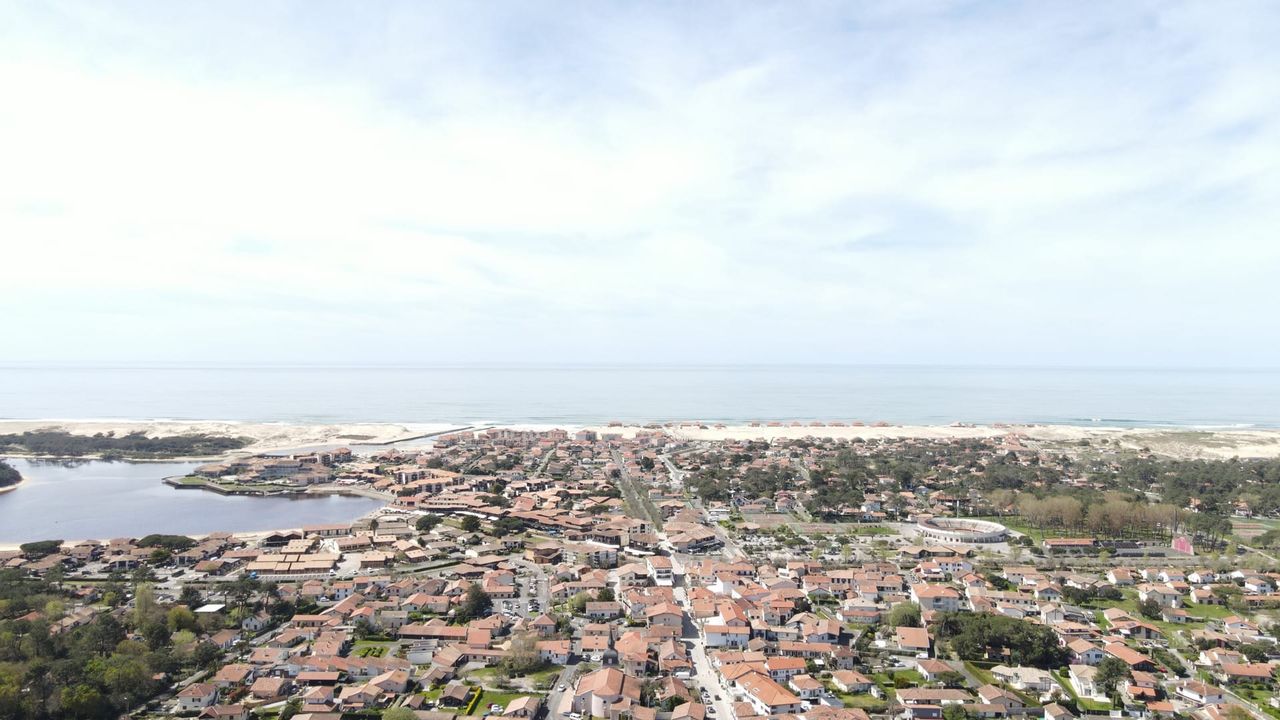 Vue aérienne d'une ville côtière avec des maisons et une plage visible au loin.