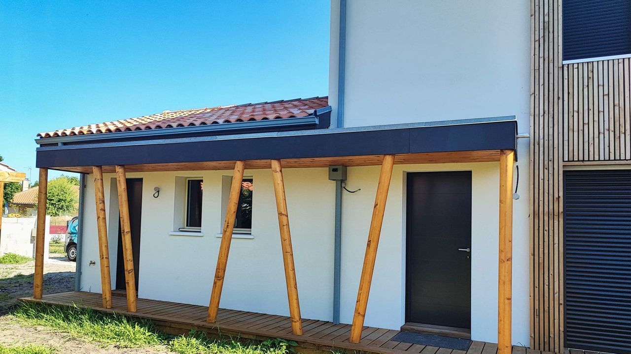 Façade d'une maison moderne avec un auvent en bois et une porte d'entrée.