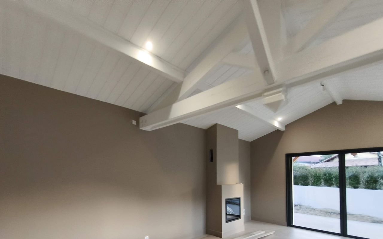 Charpente apparente et poêle – Projet Landes Habitat à Capbreton Charpente apparente peinte et poêle contemporain dans une maison rénovée à Capbreton