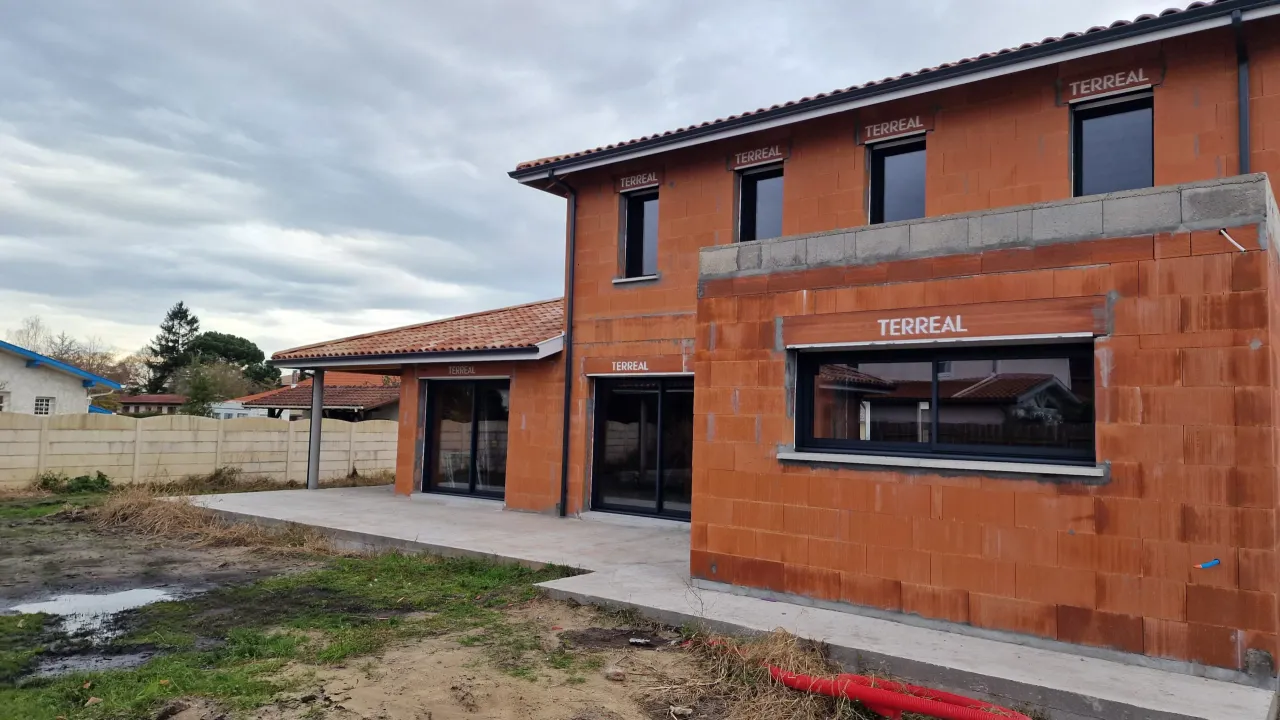 Chantier d'une grande maison individuelle avec terrasse couverte et toit en tuiles située à Tosse