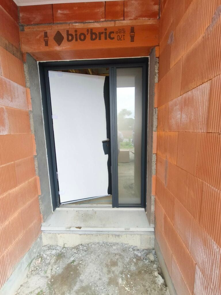 Porte d'entrée aluminium gris anthracite posée sur mur en brique Bio'bric