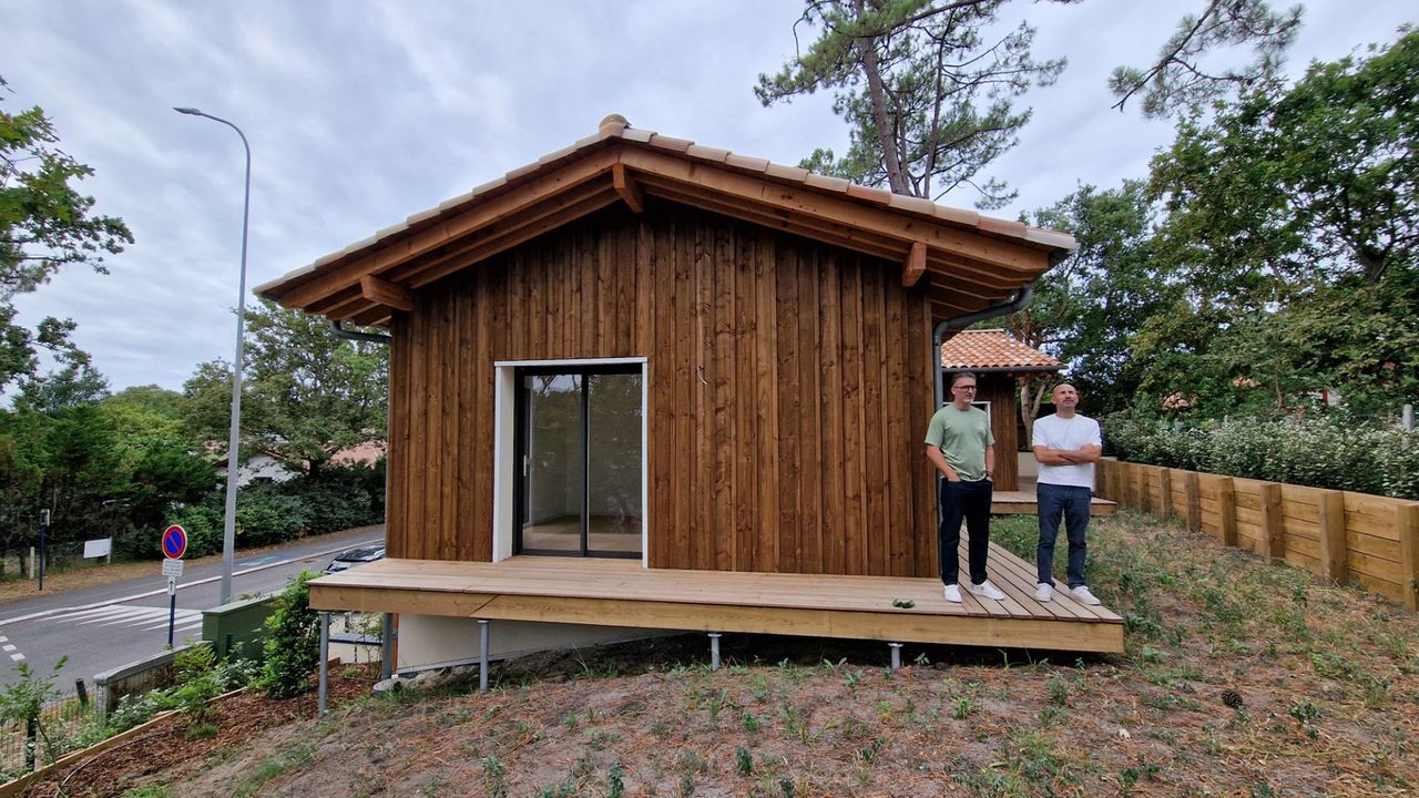 Deux hommes sur la terrasse d'une petite maison en bois avec un toit à deux pans