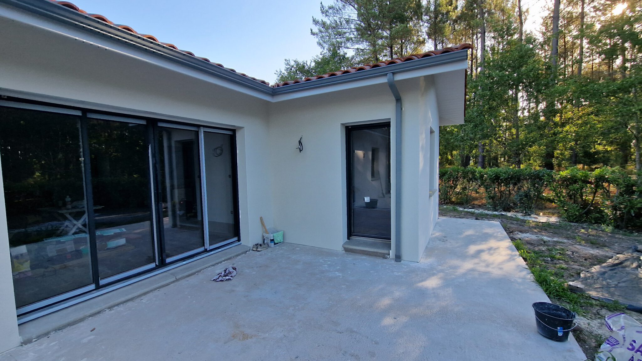 Baie vitrée coulissante en aluminium gris anthracite donnant sur la terrasse au cœur de la pinède à Herm