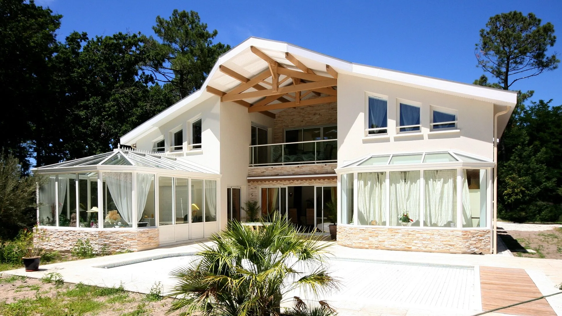 Maison R+1 contemporaine de 345 m² à Vieux-Boucau-les-Bains avec charpente apparente, double véranda et parement pierre - Construction Landes Habitat