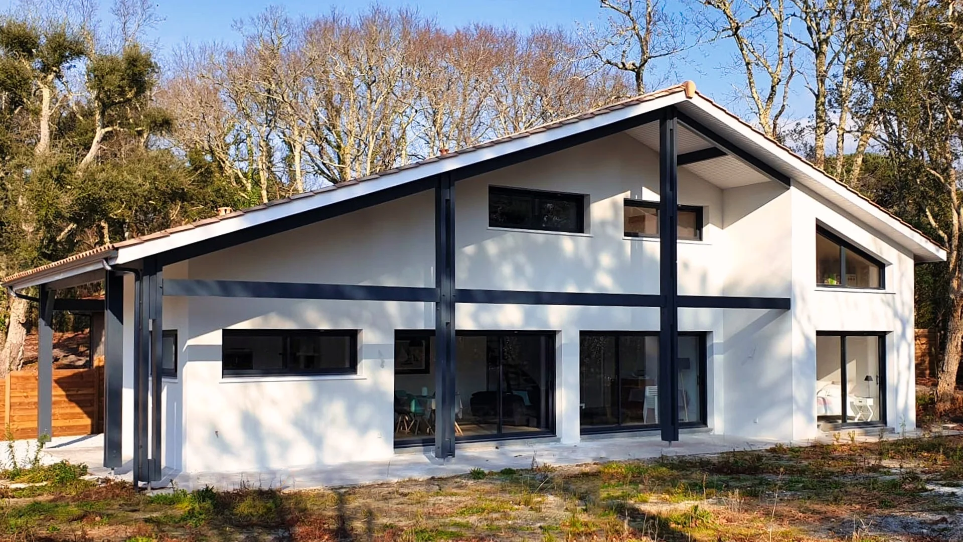 Façade moderne d'une maison familiale à Moliets avec bardage foncé et larges baies vitrées